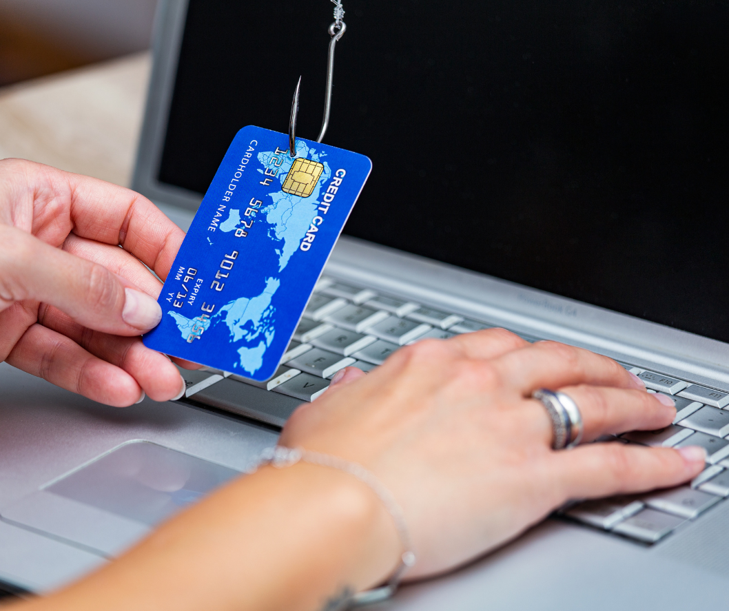 Phishing bancario: tarjeta de crédito enganchada en anzuelo frente a un ordenador portátil